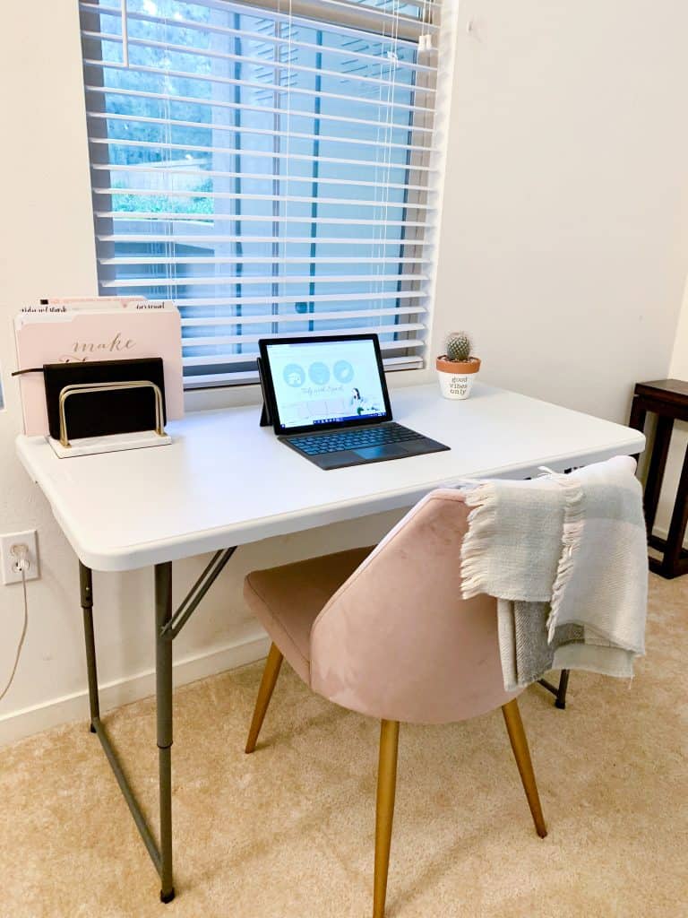 desk space with pink velvet chair and minimal laptop