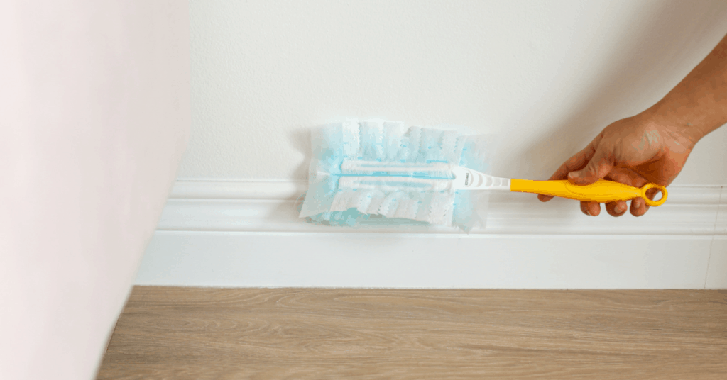 Dusting baseboards with Swiffer to show How Perfectionism gets in the way of tidying up