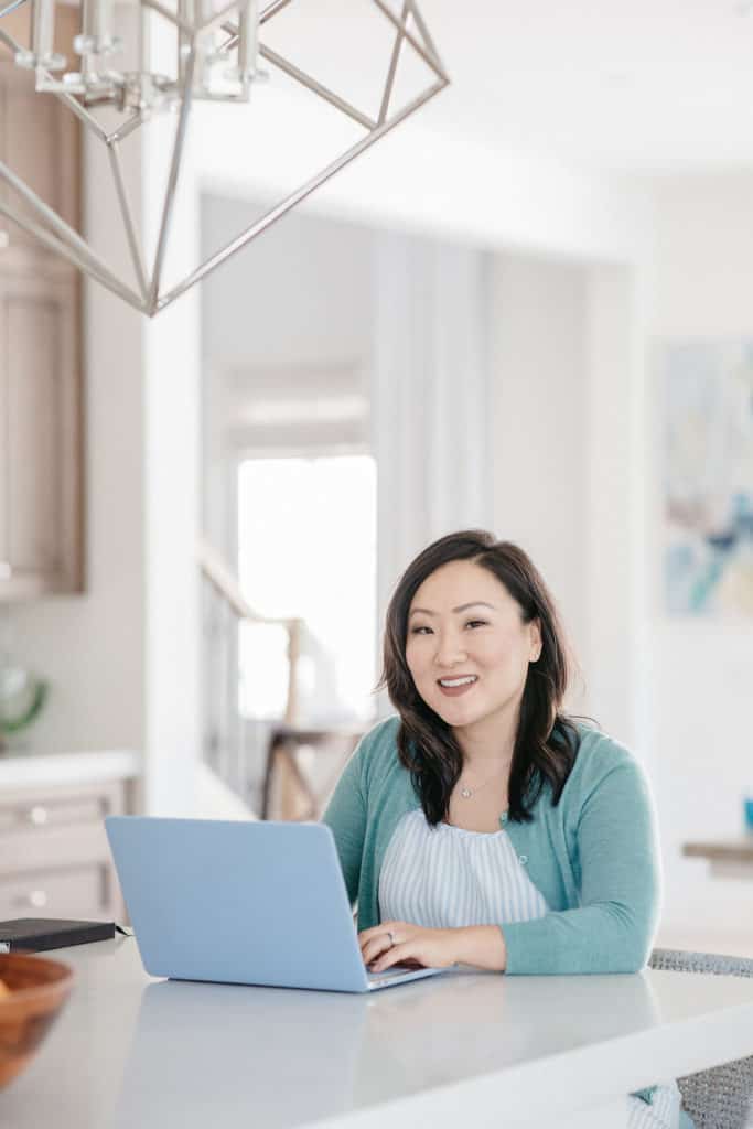 woman seated at kitchen island with laptop smiling at camera