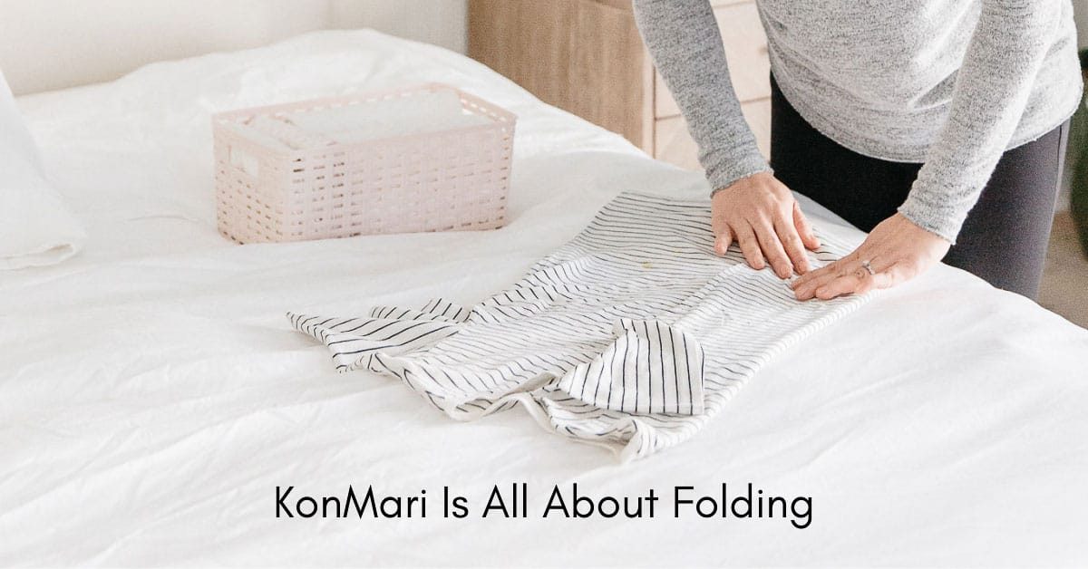 hands folding clothing on bed with text overlay konmari is all about folding